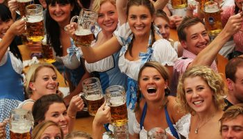 MUNICH, GERMANY - SEPTEMBER 18: Visitors of the Oktoberfest toast with beer mugs during the opening day of the Oktoberfest at Theresienwiese on September 18, 2010 in Munich, Germany. 2010 marks the 200th anniversary of Oktoberfest.The Oktoberfest tradition started in 1810 to celebrate the October 12th marriage of Bavarian Crown Prince Ludwig to the Saxon-Hildburghausen Princess Therese. The citizens of Munich were invited to join in the festivities which were held over five days on the fields in front of the city gates. The main event of the original Oktoberfest was a horse race. The world's biggest beer festival will last this year from September 18 to October 4.  (Photo by Alexandra Beier/Getty Images)