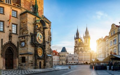 View to the astronomical clock and the old town square of Prague with Tyn Church in the background during sunrise time without people. Czech Republic